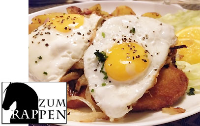 Kalbsschnitzel mit Spigelei, gerösteten Zwiebeln, Bratkartoffeln und Salat.